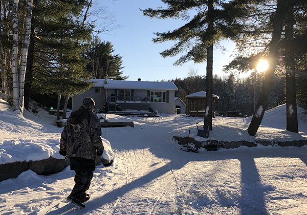 Man walking towards a cottage in the snow.